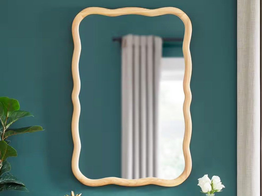 wavy wood framed mirror on a teal wall