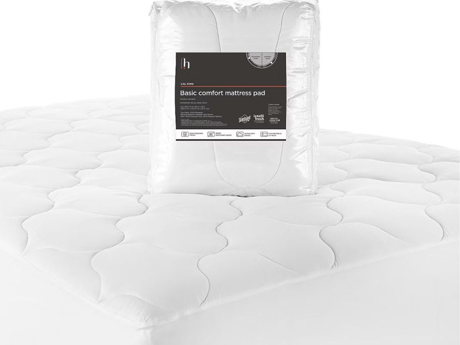 A Home essentials Mattress pad in the package on a mattress covered in a mattress pad