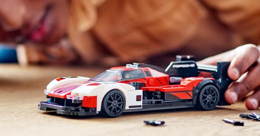 boy playing with red and white LEGO Porsche