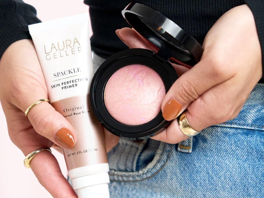 woman holding a laura geller primer and blush