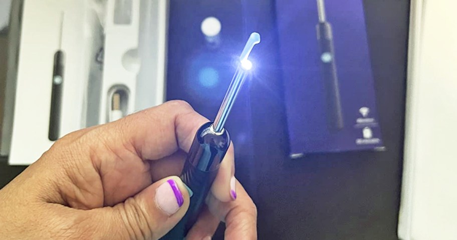 hand holding a lighted ear wax removal tool