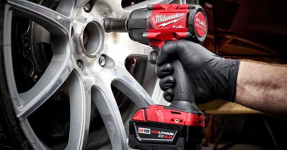 man using a Milwaukee Impact Wrench on car wheel