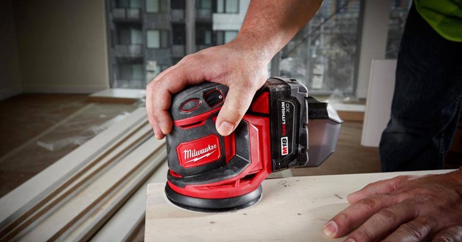 man using Milwaukee Orbit Sander on wood