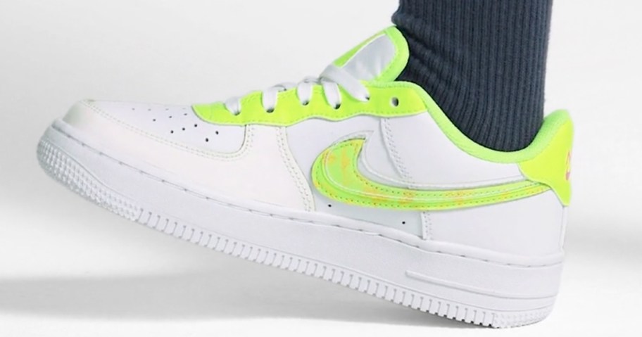 kid wearing white nike sneaker with bright yellow nike symbol