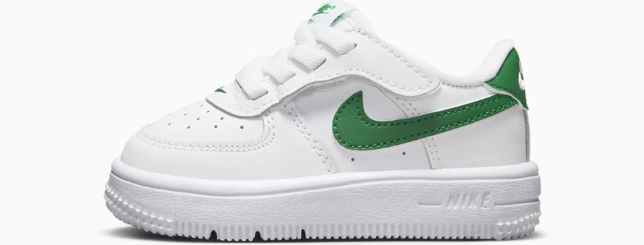 white baby sneaker with green nike logo