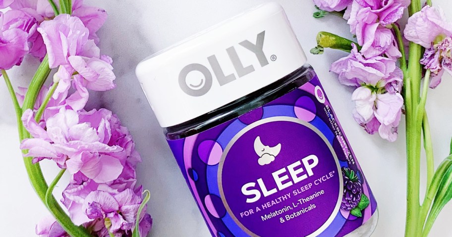 purple bottle of OLLY Sleep Gummies near purple flowers