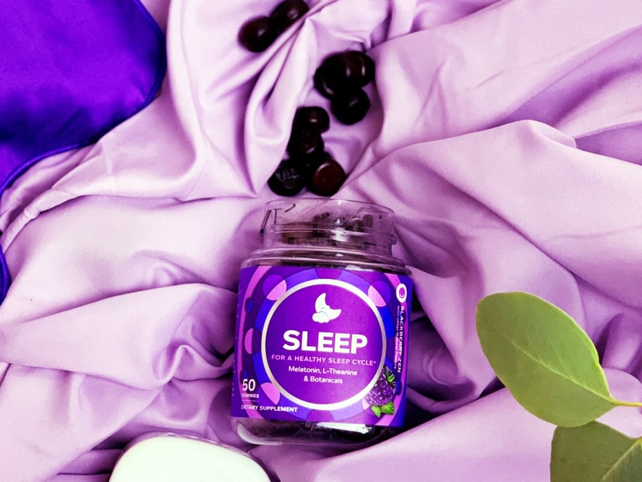 OLLY Sleep Gummy bottle spilled on purple bed sheets