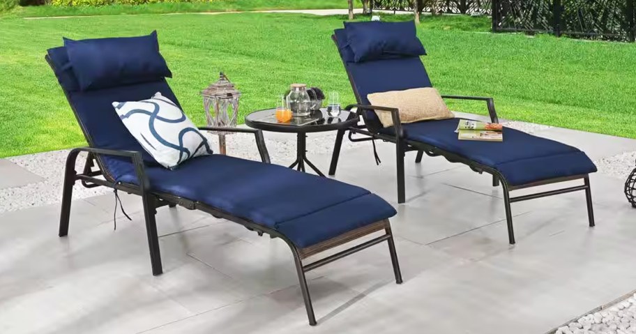 two chaise lounge chairs with blue cushions and matching side table