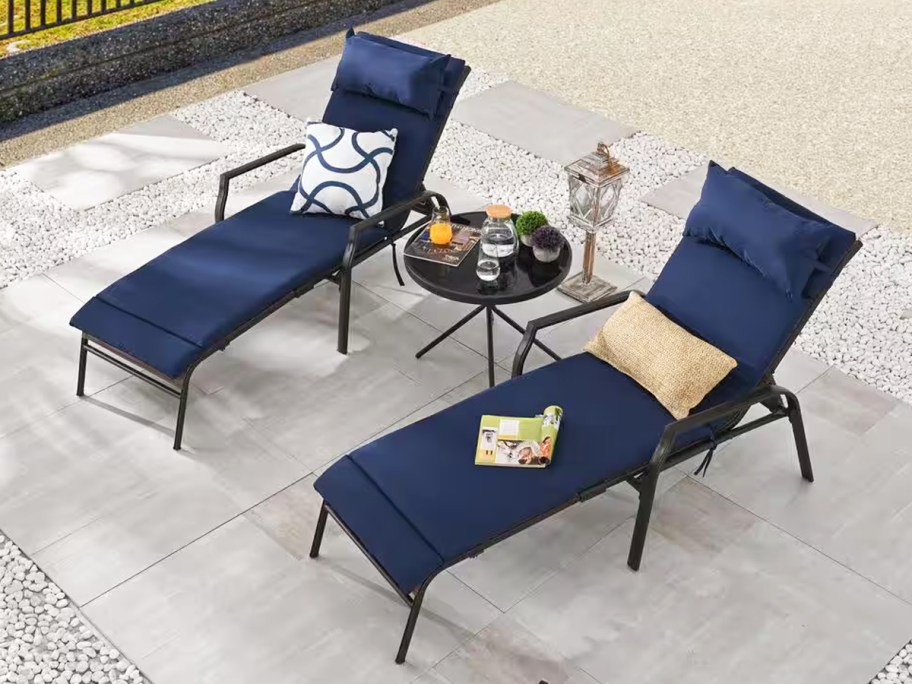 two chaise lounge chairs with blue cushions and matching side table