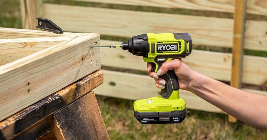 person using ryobi impact driver on wood