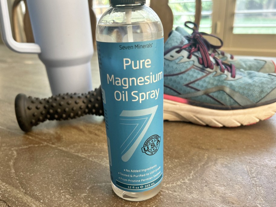 bottle of Seven Minerals Magnesium Oil Spray near foot roller, running shoes, and tumbler