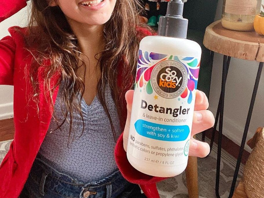 A girl holding a So Cozy Kids' Detangler & Leave-In Conditioner Spray