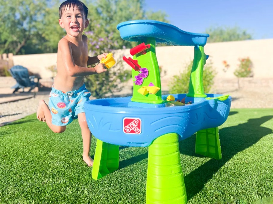 boy playing with water table outside