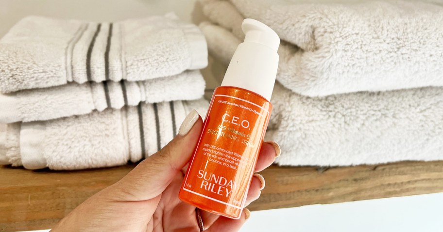 hand holding an orange bottle of Sunday Riley C.E.O. Vitamin C Brightening Serum