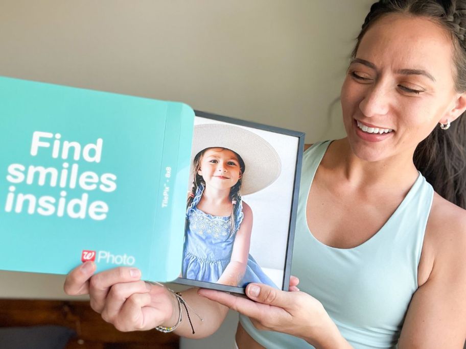 Woman opening a Walgreens photo box with a TilePix Tile inside