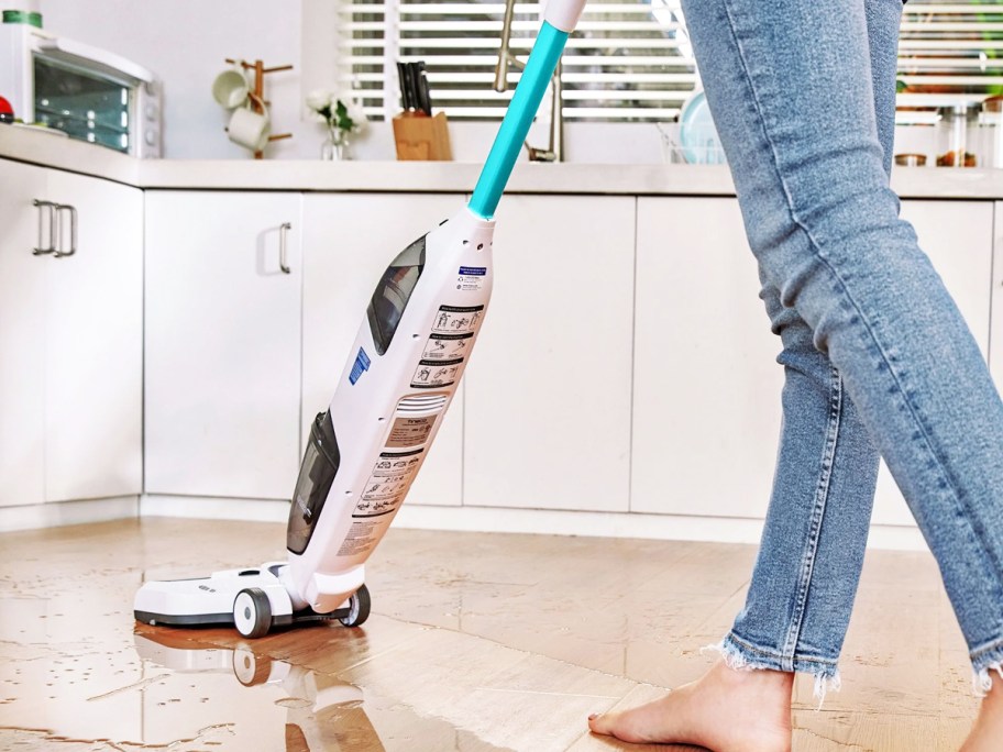 woman using vacuum mop to clean up spill on floor