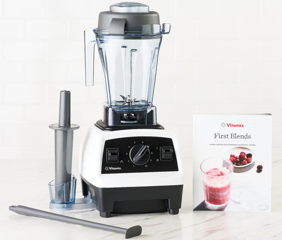 white and black vitamix blender, tamper, and cookbook on counter