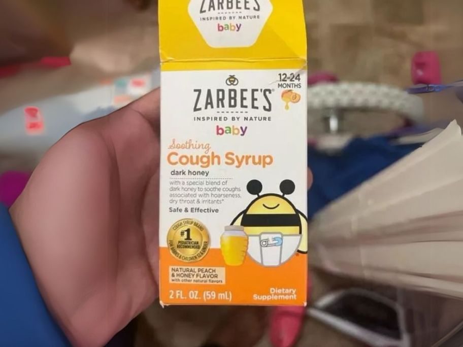 hand holding Zarbee's Baby Soothing Cough Syrup 2oz Bottle