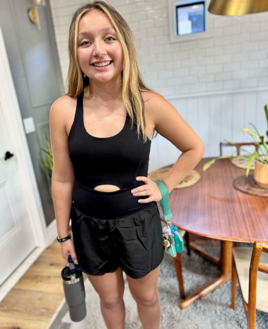 girl modeling black athletic jumpsuit holding reusable water bottle 