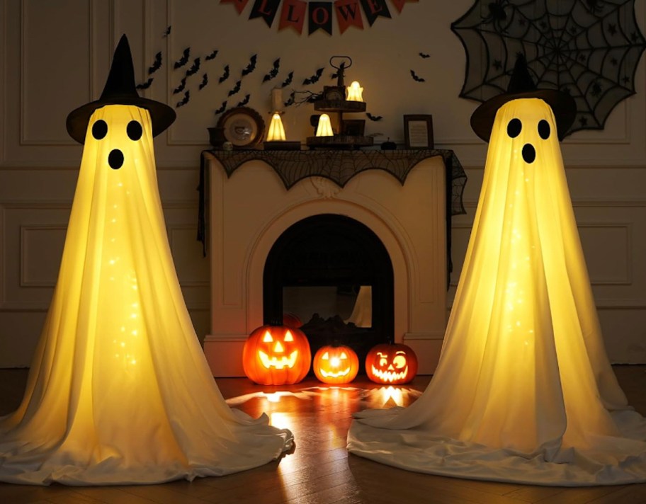 prelit ghosts in front of fireplace with jackolanterns