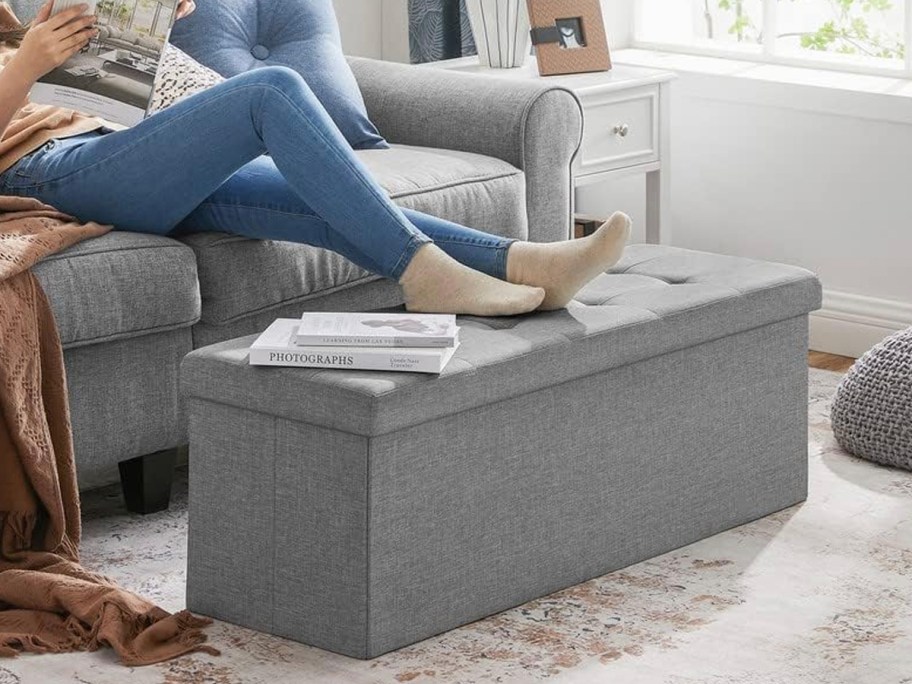 person with feet on gray ottoman 