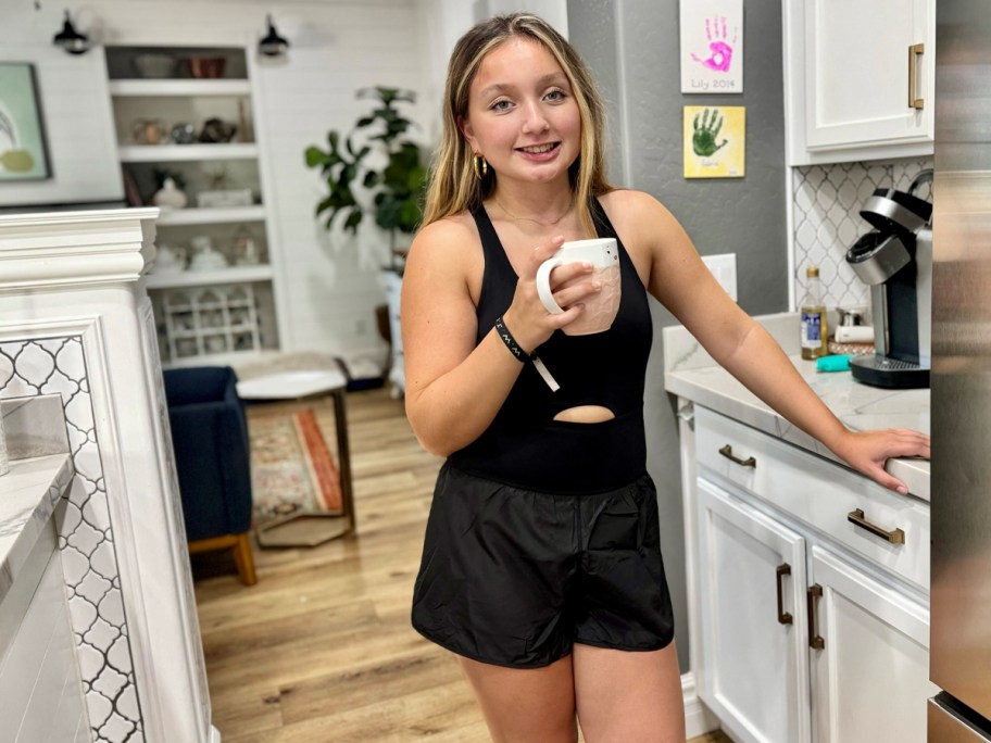 woman wearing black romper holding coffee cup 