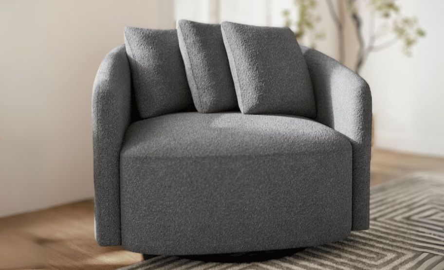 a charcoal colored boucle swivel chair in a livingroom on a rug