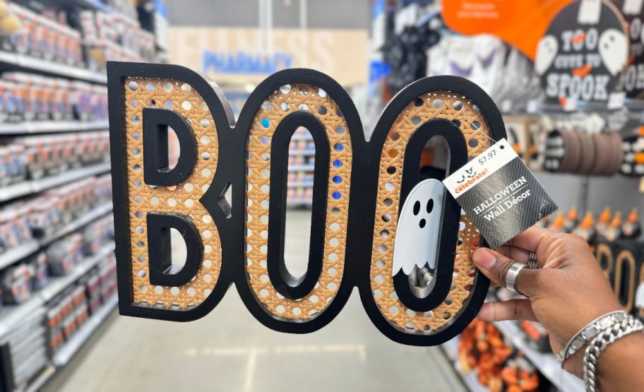 a woman's hand holding a boo wicker hanging decor