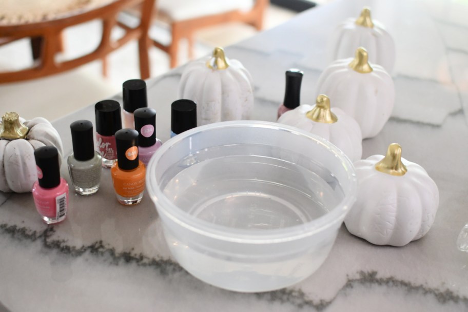 bowl of water with supplies to make nail polish marbled pumpkins