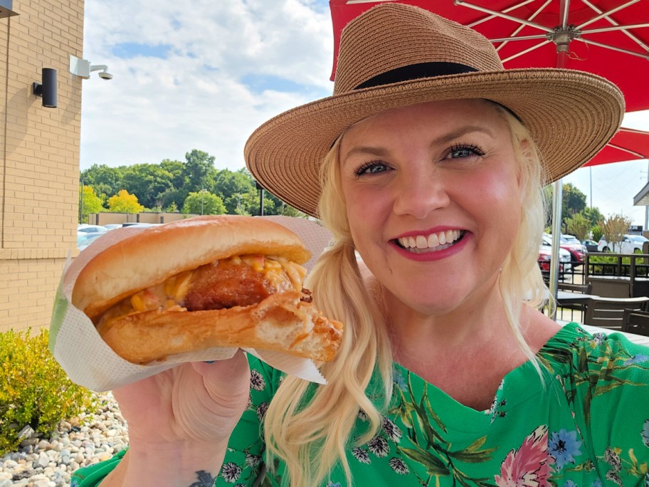 smiling woman holding a chick fil a pimento cheese chicken sandwich