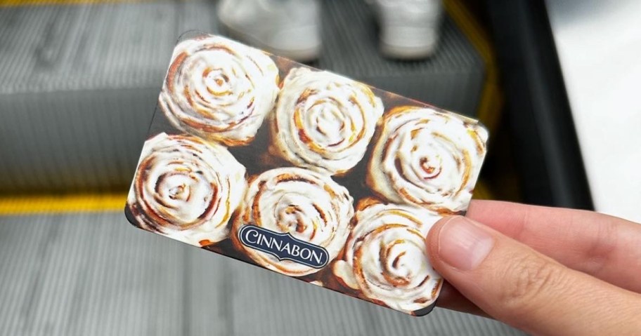 holding a Cinnabon gift card in front of escalator