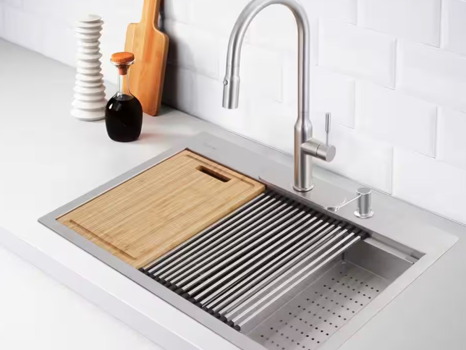 stainless steel kitchen faucet and sink in kitchen with cutting board and strainer