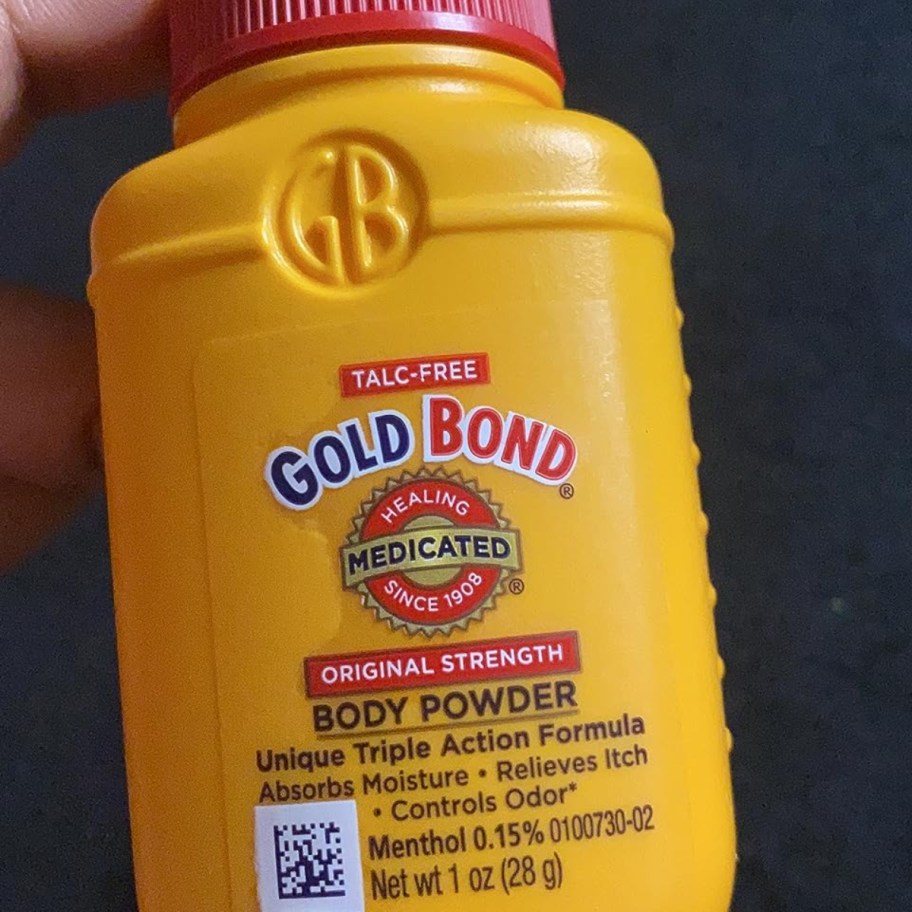 holding a trial size of Gold Bond powder 