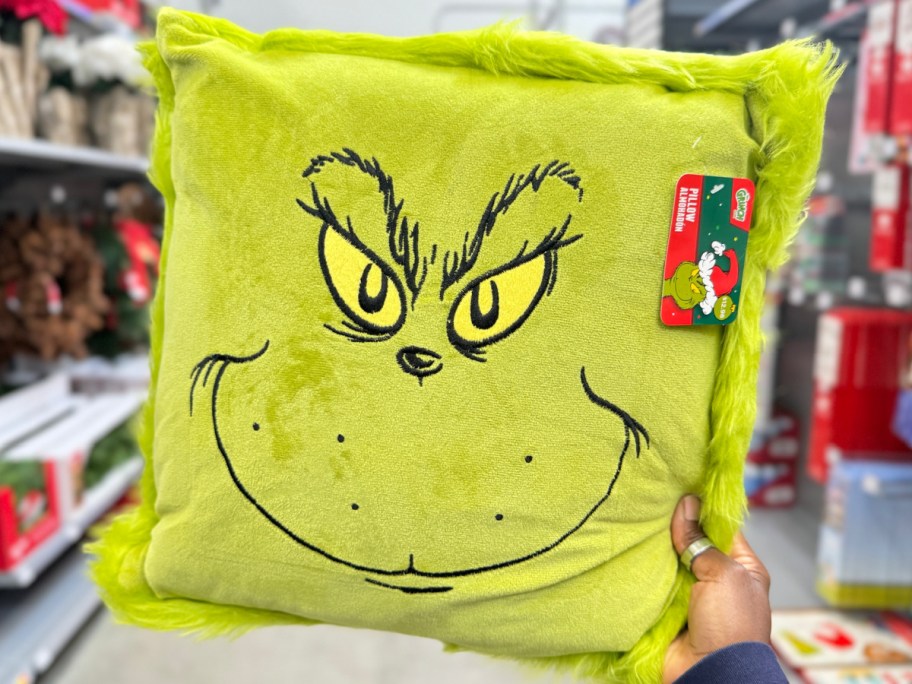 grinch throw pillow in womans hand at the store