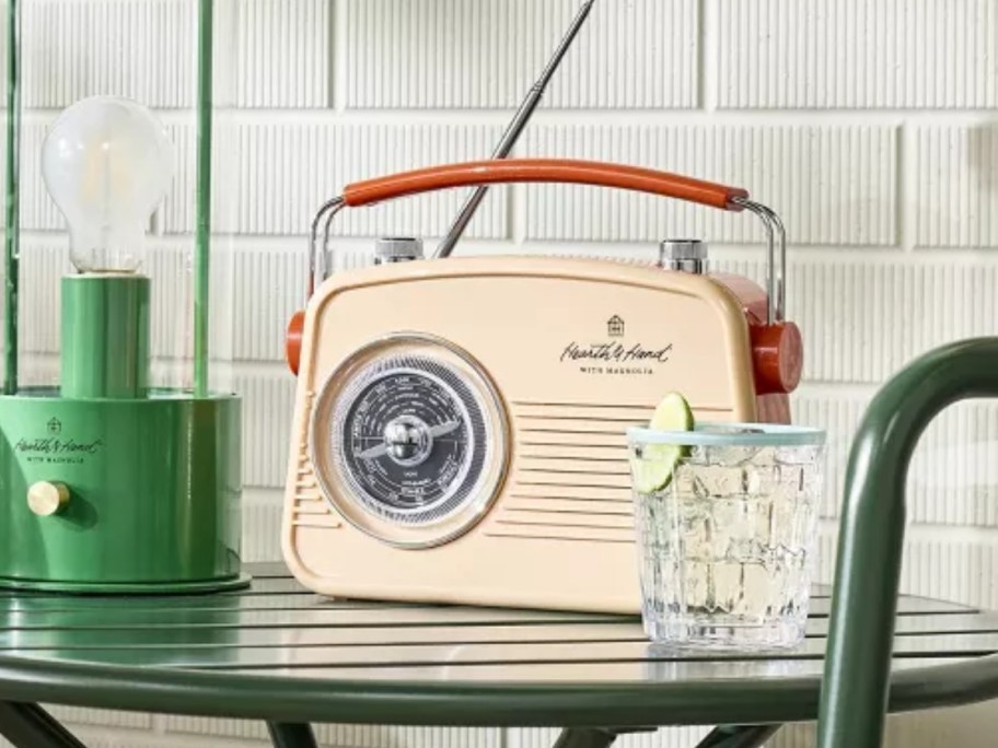 cream and orange retro style radio on a bistro table next to a glass of water