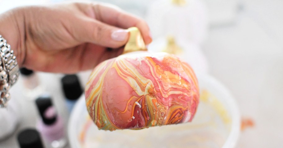 holding a diy marbled painted white pumpkin 