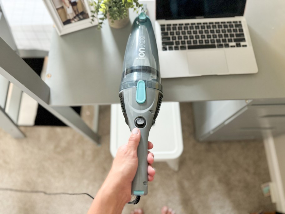 hand vacuuming desk with laptop on it