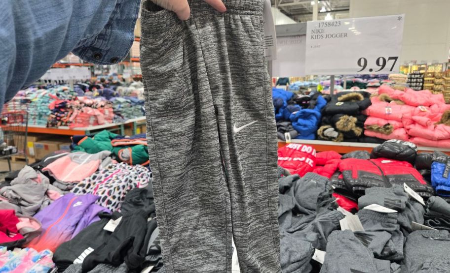 a woman hand holding a pair of kids nike joggers