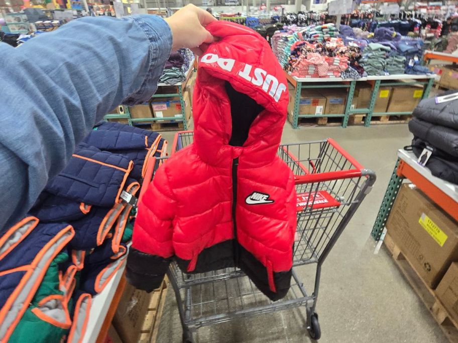 woman hand holding a red and black kids nike puffer jacket