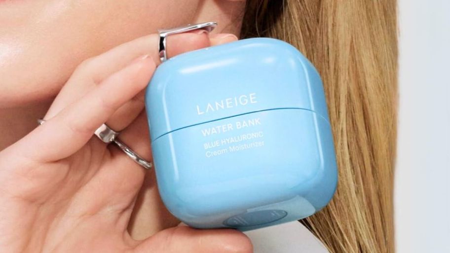 a womans hand holding a jar of laneige water bank moisturizer