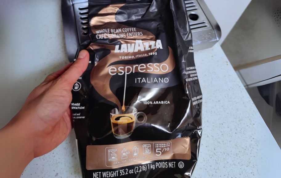 a hand holding a bag of lavazza espresso roast ground coffee