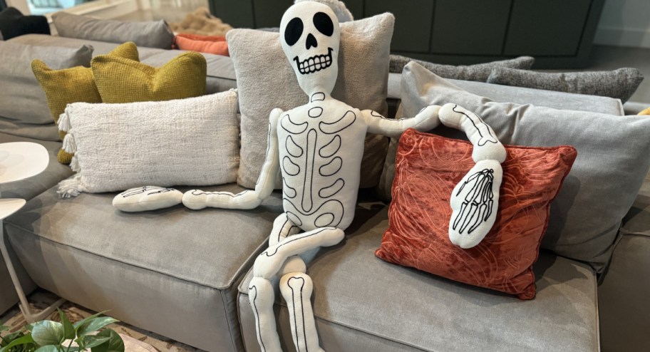 lifesize skeleton sitting on ouch with pillows next to it