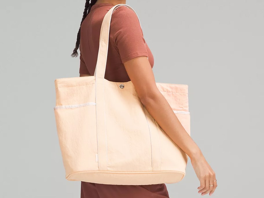 woman in a brown outfit with a light orange tote bag