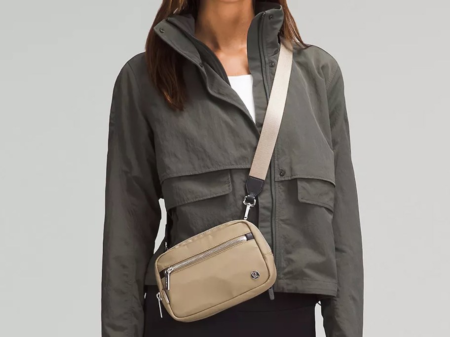 woman in a grey jacket with a tan crossbody bag