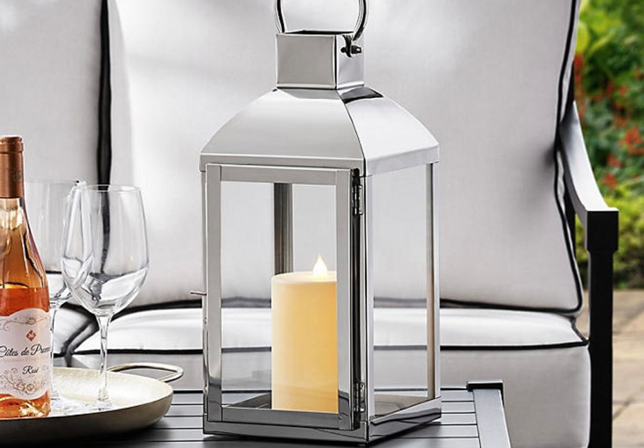 gray lantern with candle inside on table outdoors