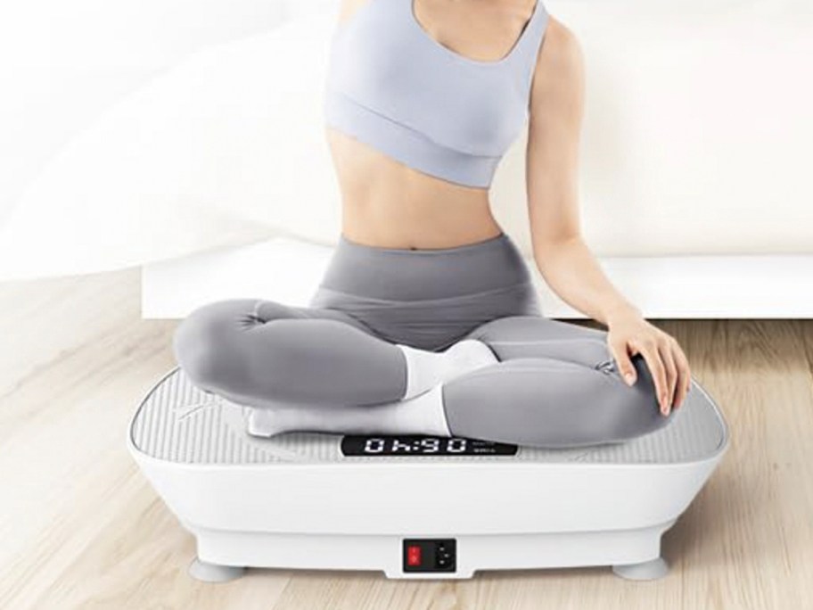 woman sitting on white exercise vibration plate machine 