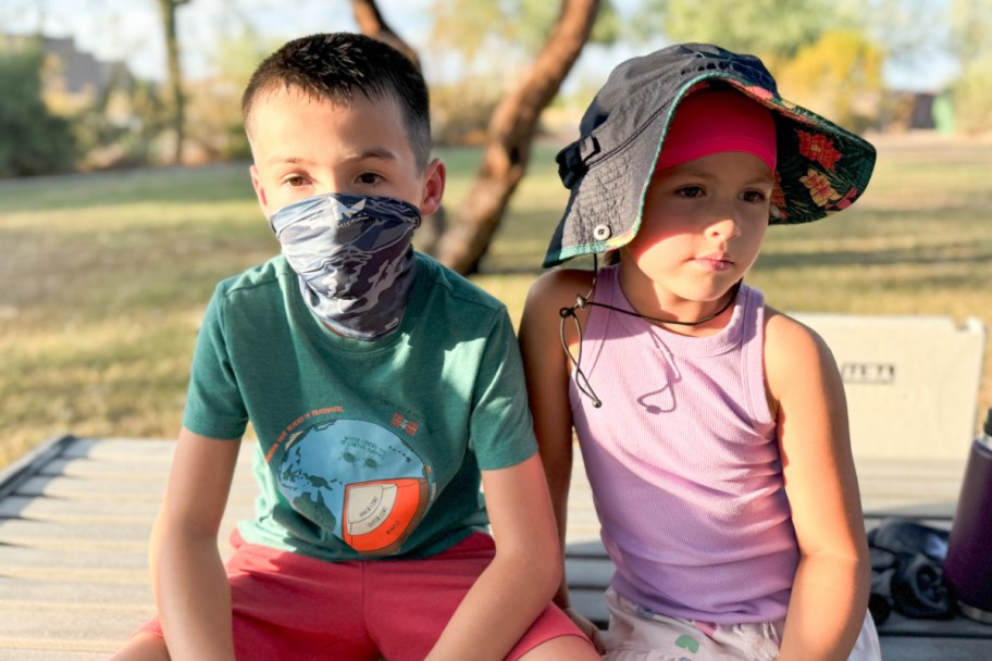 girl and bow sitting on park bench wearing cooling gaiters and hats