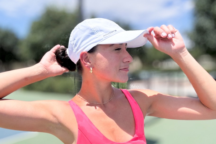 woman holding white cooling hat on head