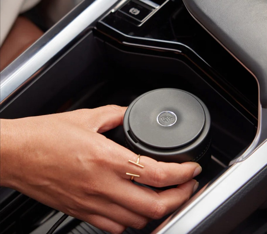 hand grabbing car diffuser in cup holder