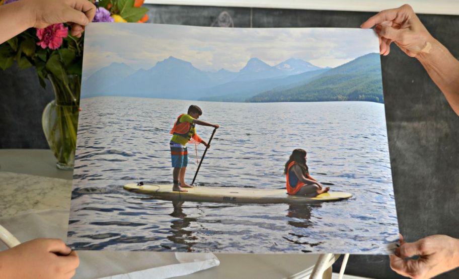 two people's hands holding the corners of a repositionable poster